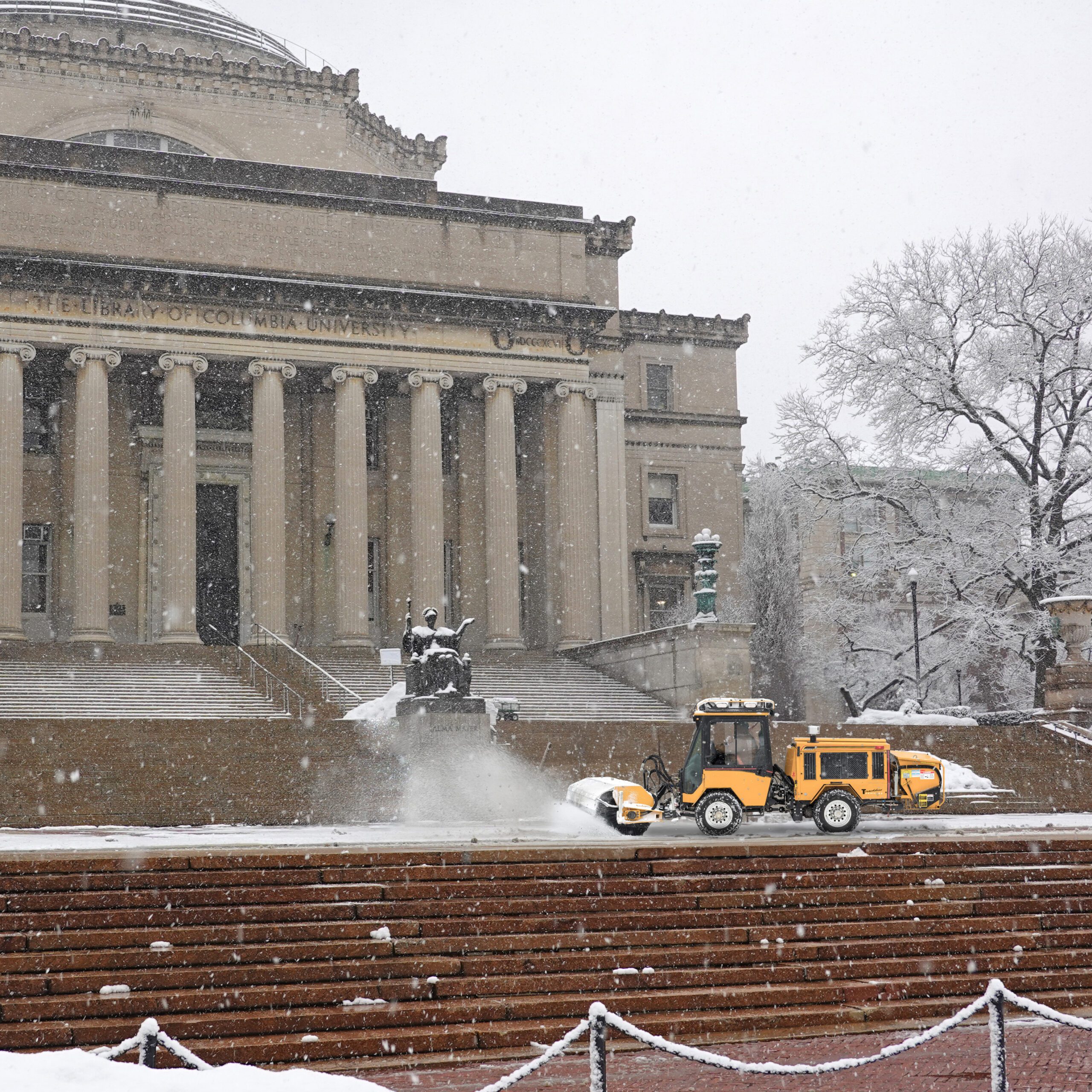 trackless vehicles tractor sweeping snow from steps of columbia university library campus