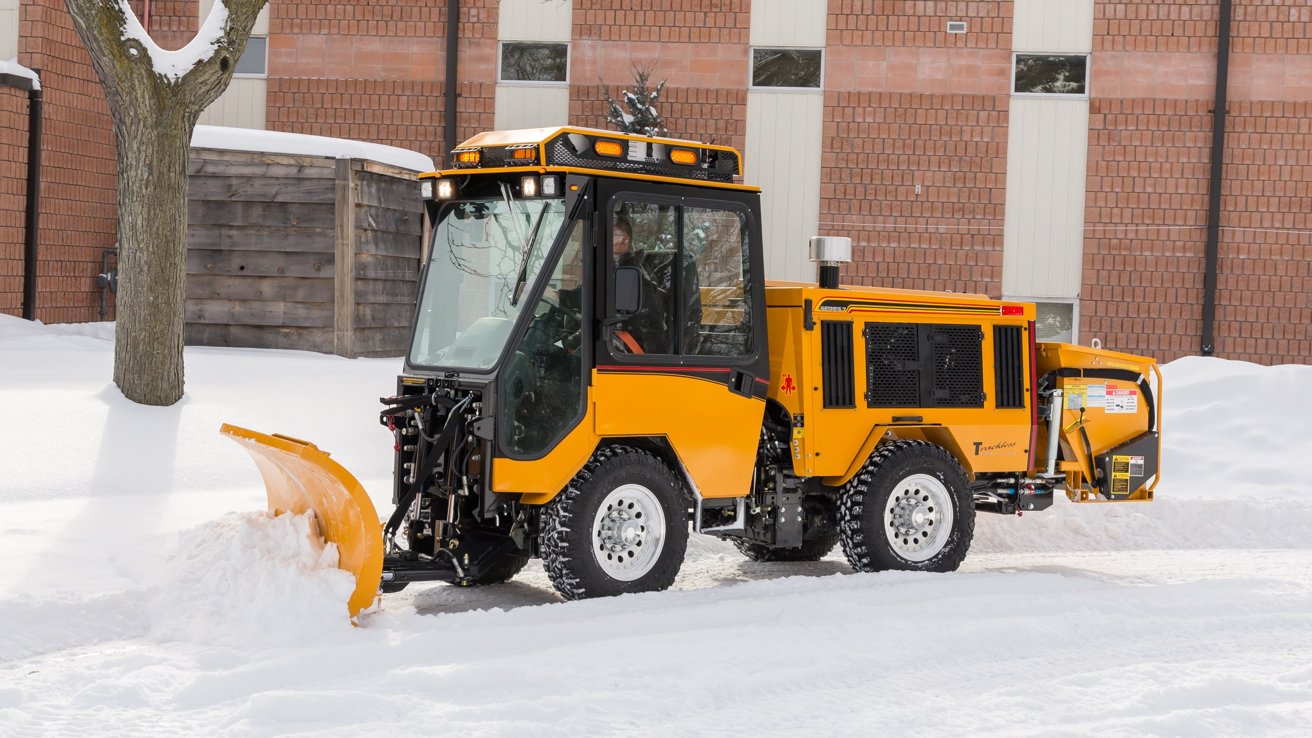 trackless mt7 sidewalk tractor machine with double trip plow attachment plowing snow on sidewalk