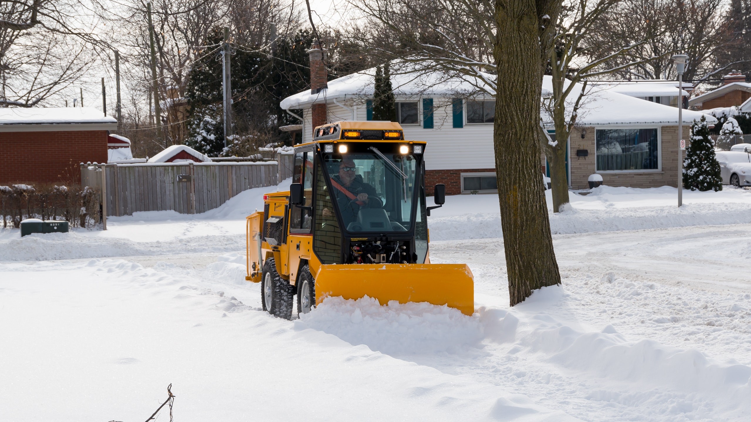 trackless mt7 sidewalk tractor machine with double trip plow attachment plowing snow on sidewalk