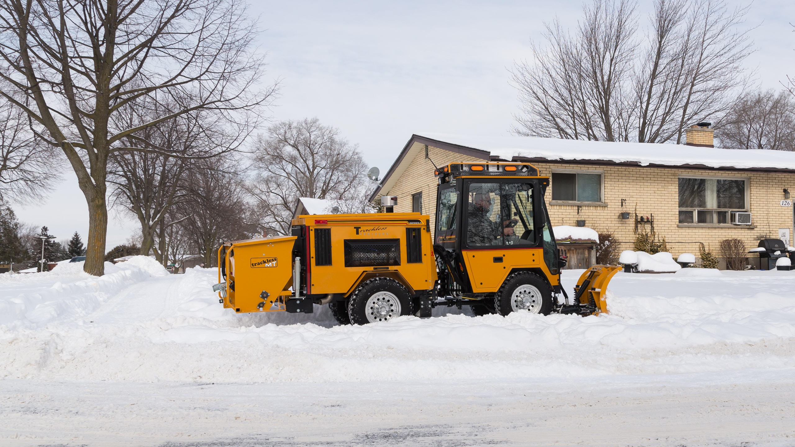 trackless mt7 sidewalk tractor machine with double trip plow attachment plowing snow on sidewalk