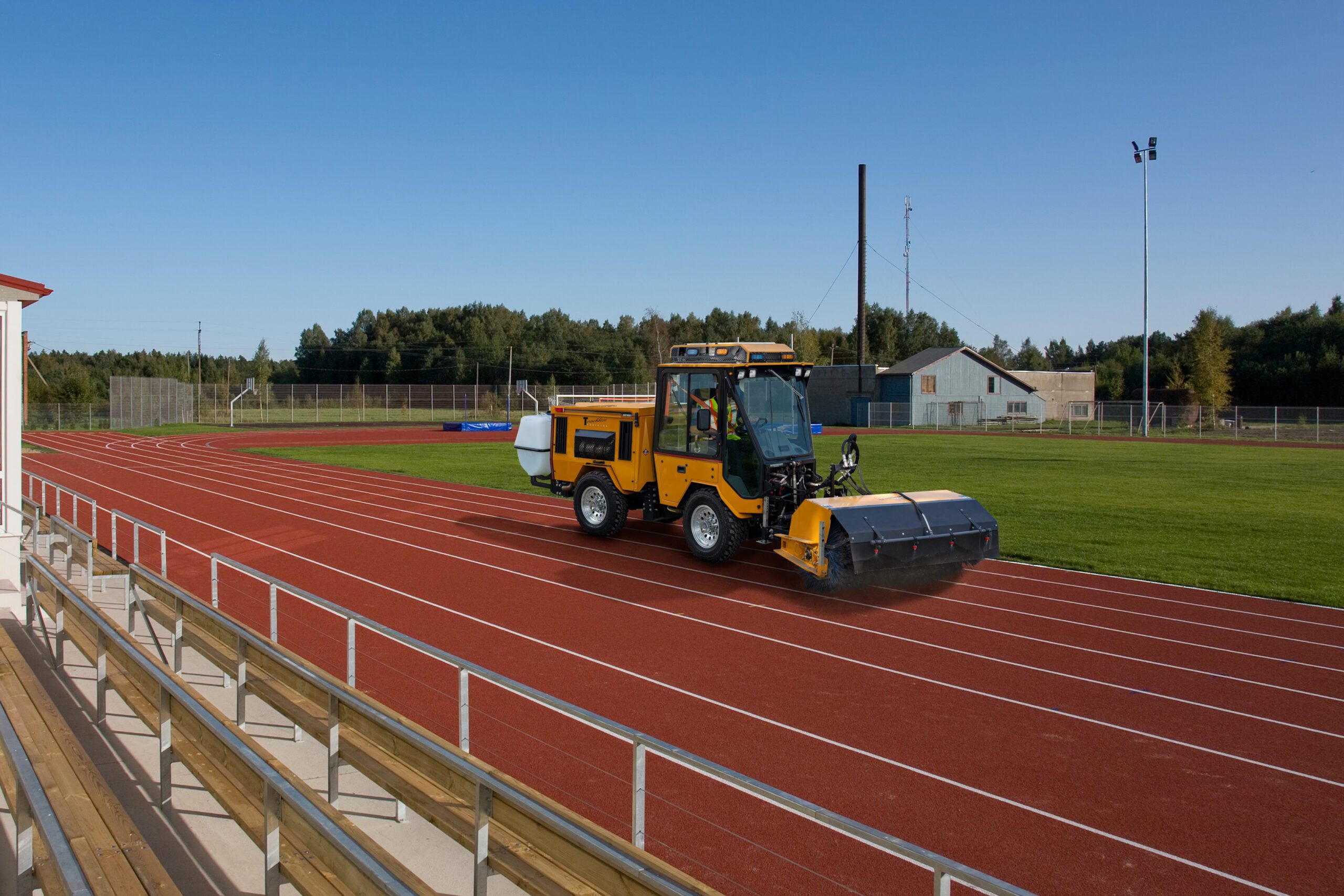 trackless vehicles power angle sweeper attachment sweeping dirt and debris from a university or college sports running track