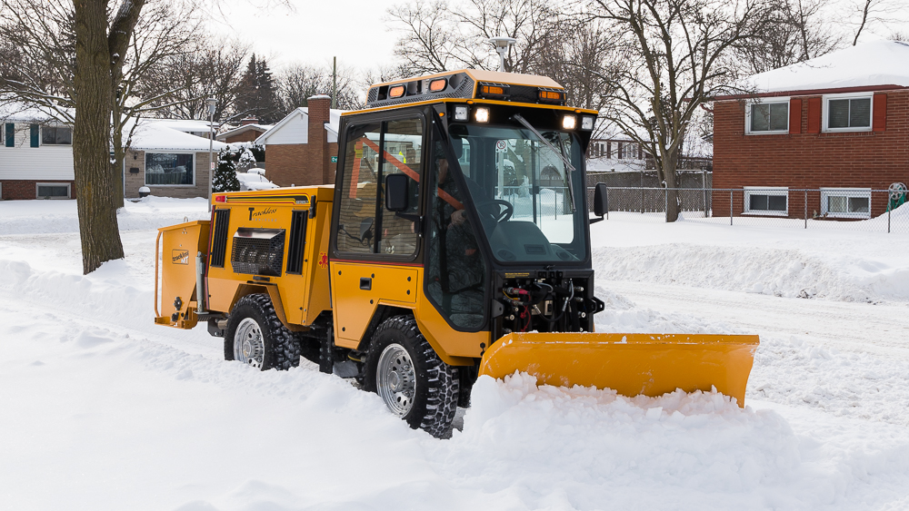 trackless vehicles double trip plow attachment on sidewalk tractor in snow front view