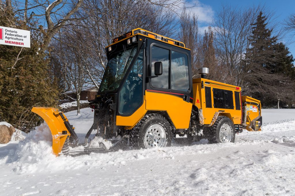 trackless vehicles double trip plow attachment on sidewalk tractor in snow side view