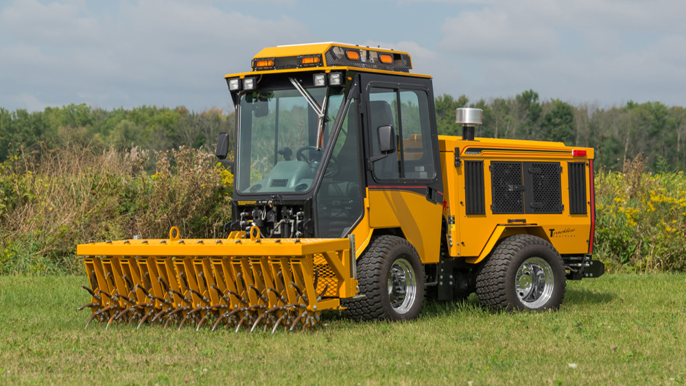 trackless vehicles aerator attachment on sidewalk municipal tractor in field front side view