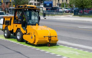 trackless vehicles pickup sweeper attachment on sidewalk municipal tractor side view