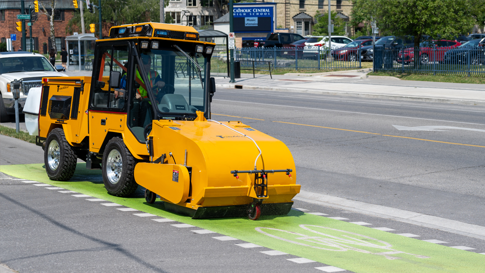 trackless vehicles pickup sweeper attachment on sidewalk municipal tractor side view