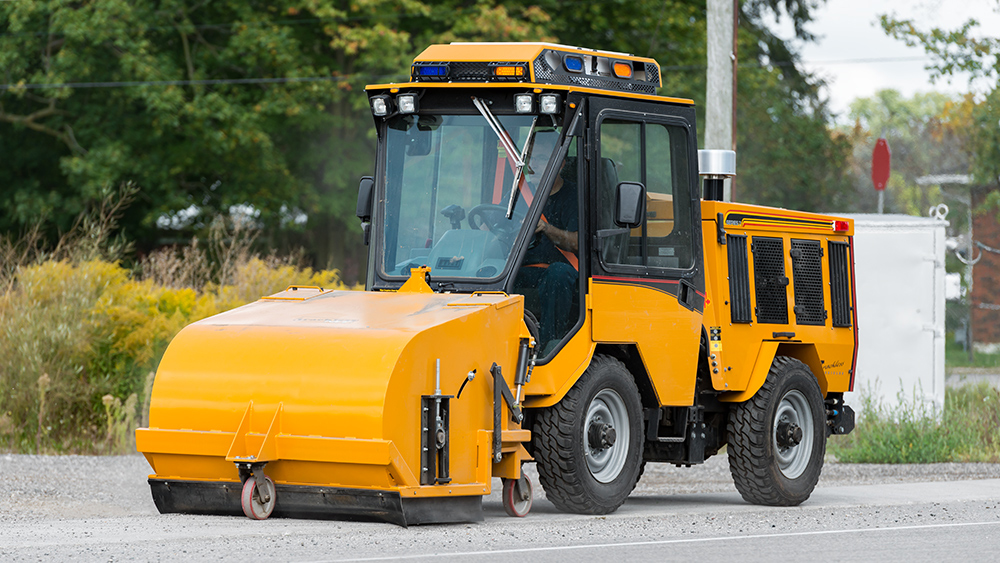 trackless vehicles pickup sweeper attachment on sidewalk municipal tractor working on sidewalk