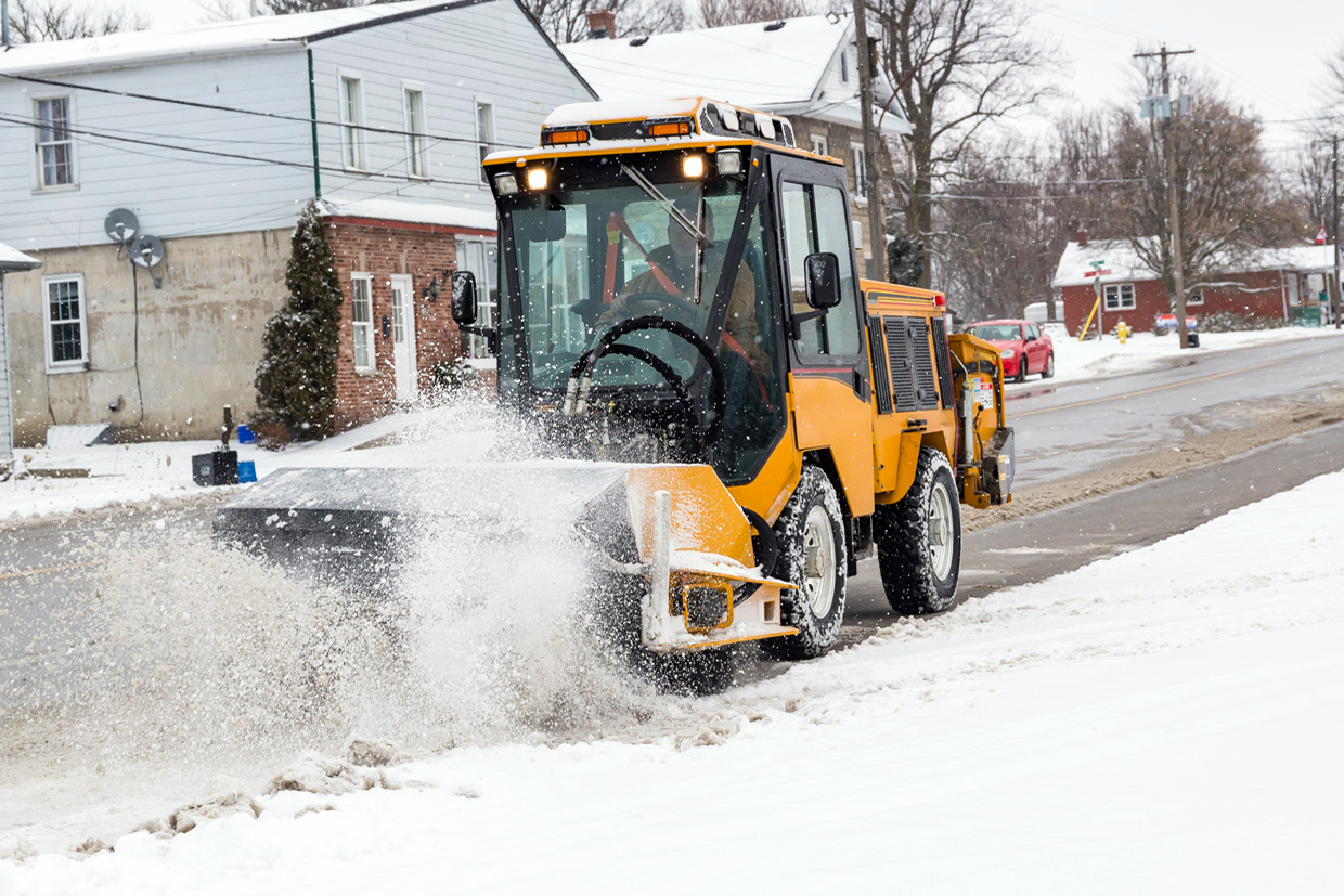 trackless vehicles power angle sweeper attachment on sidewalk municipal tractor working on sidewalk in snow side view