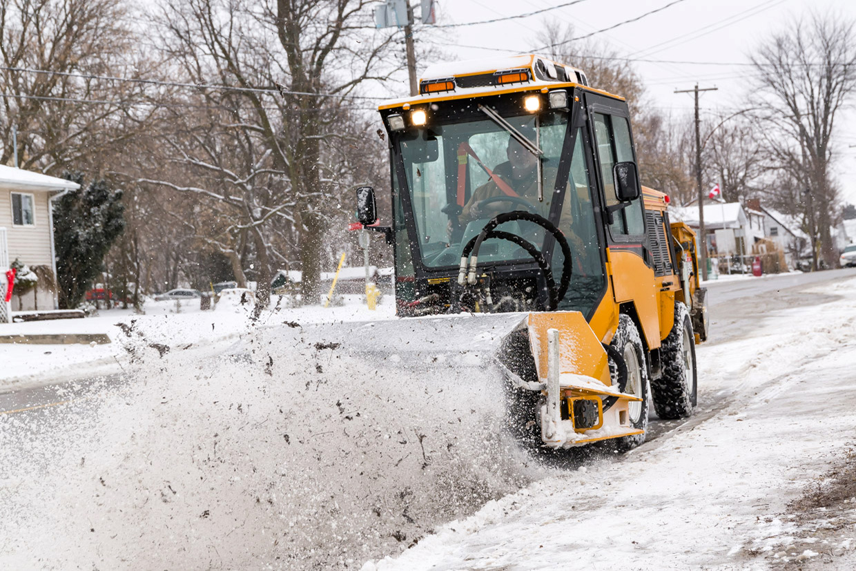 trackless vehicles power angle sweeper attachment on sidewalk municipal tractor working on sidewalk front view in snow