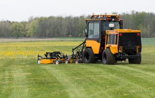 trackless vehicles progressive turf 14' mower attachment on sidewalk municipal tractor mowing grass rear view