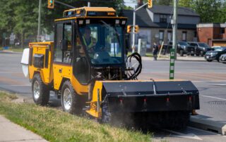 trackless vehicles power angle sweeper attachment on sidewalk municipal tractor sweeping dirt on road